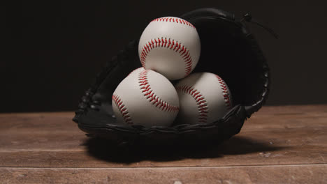 Close-Up-Studio-Baseball-Still-Life-With-Balls-In-Catchers-Mitt-On-Wooden-Floor-3